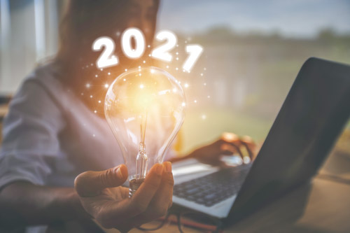 person at laptop holding light bulb showing 2021