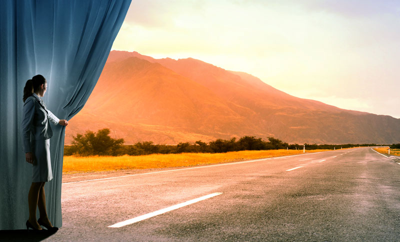 woman pulling back curtain to reveal road extending to horizon